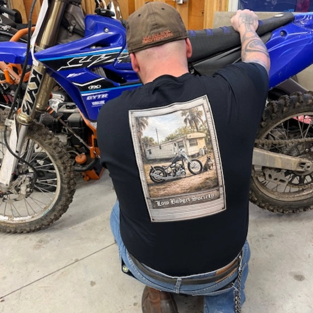 Man working on a workbench with "Priorities" T shirt featured